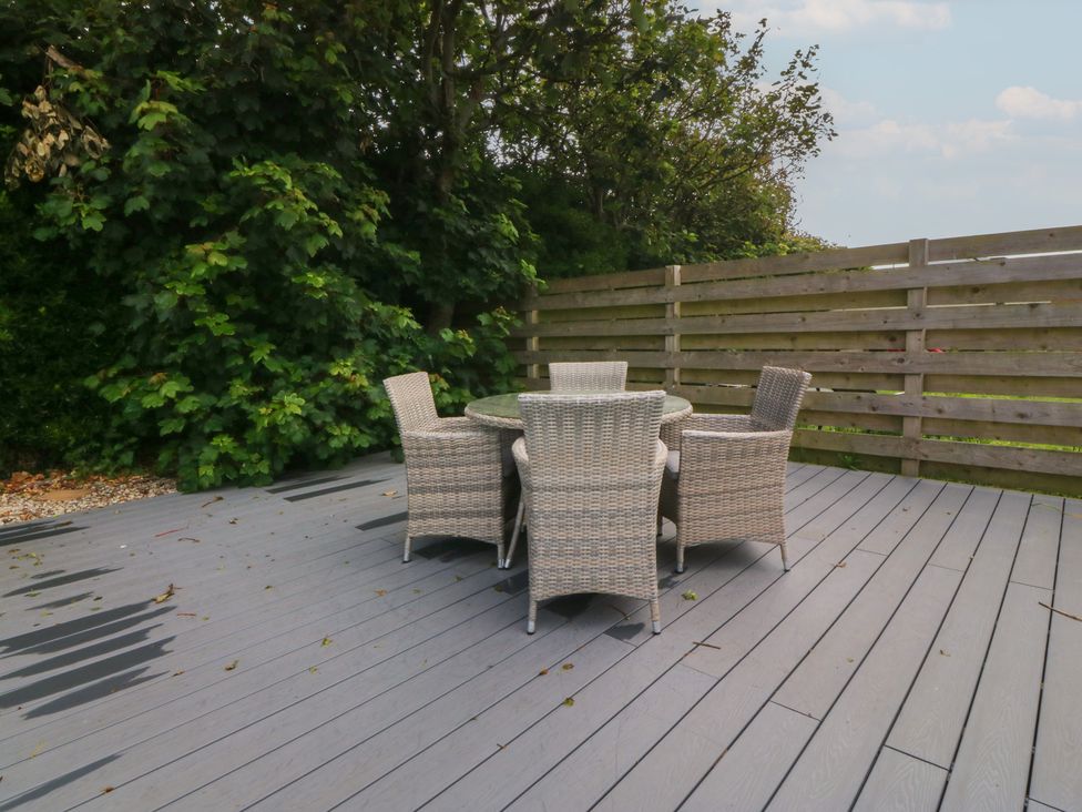 A garden with a table and chairs on a deck at Porth Ewyn House in Trearddur Bay