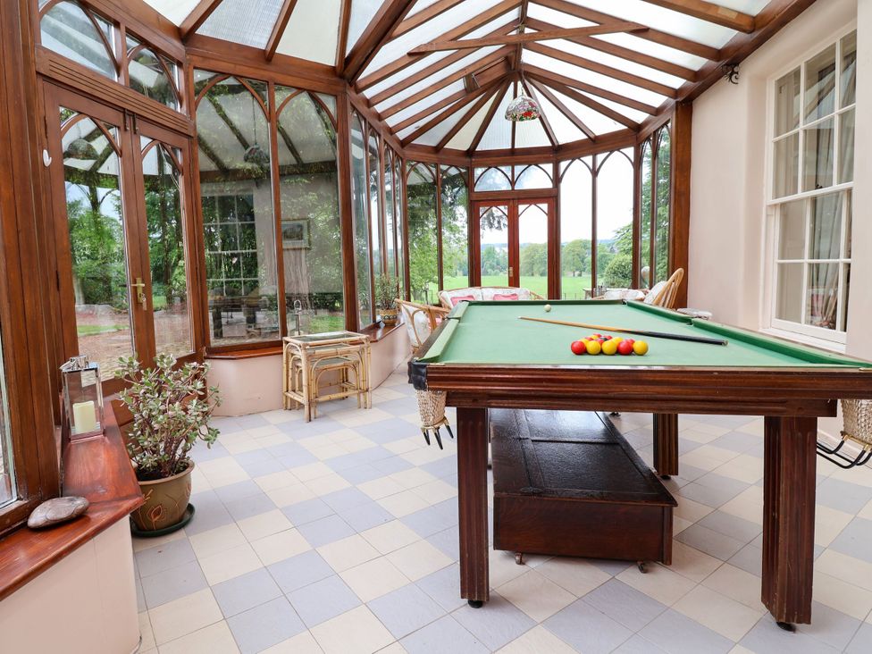A conservatory with a pool table and seating at Parkfields House in Stoke-on-Trent