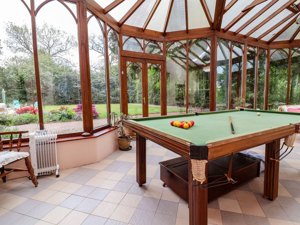 A conservatory with a pool table and garden view at Parkfields House in Stoke-on-Trent