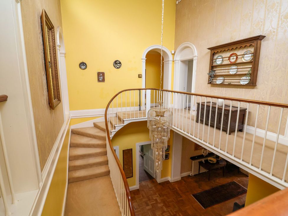 A hallway with stairs and chandelier at Parkfields House Stoke-on-Trent