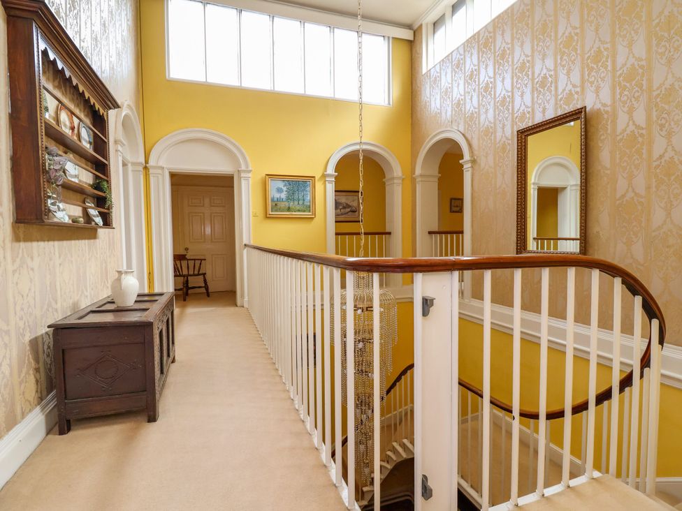 A hallway with a staircase and a chandelier at Parkfields House in Stoke-on-Trent