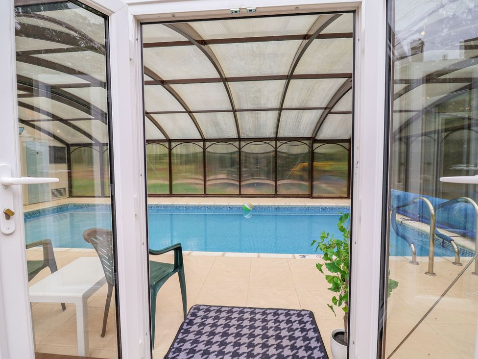 A conservatory with a swimming pool and sliding door at Parkfields House in Stoke-on-Trent