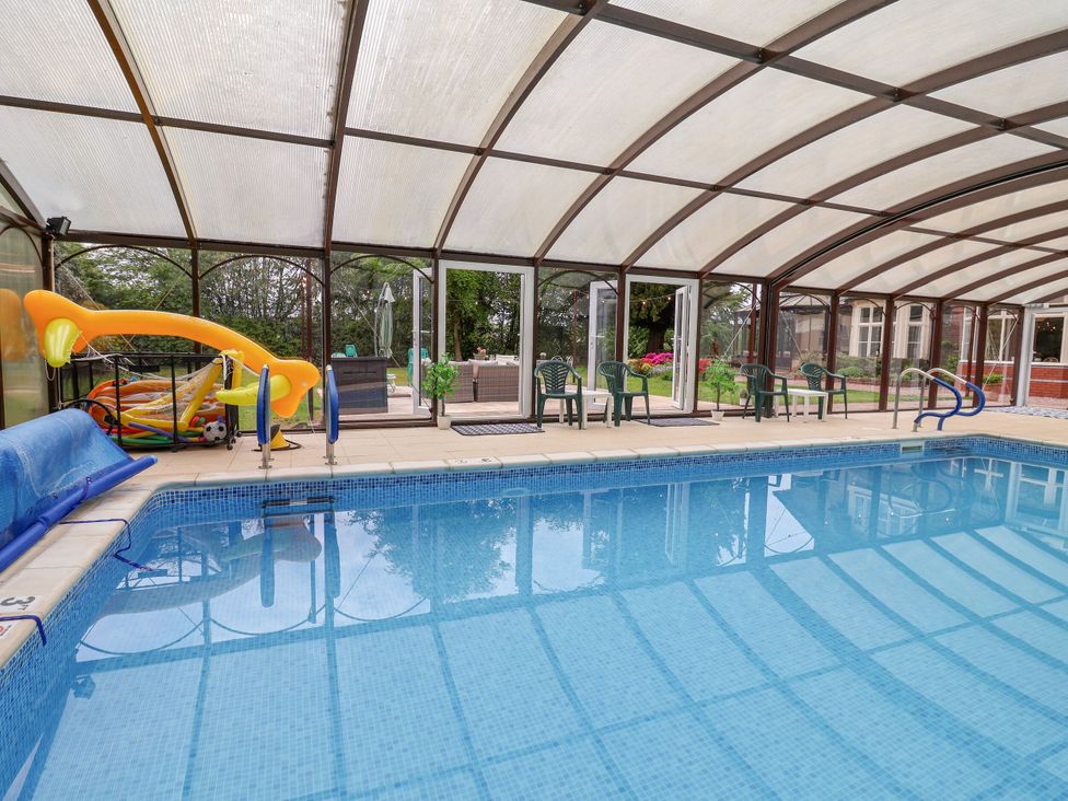 An indoor pool with deck chairs and sliding toys at Parkfields House Stoke-on-Trent