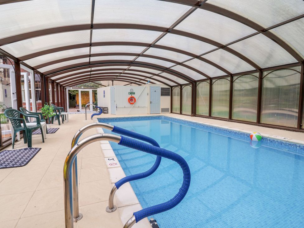 An indoor swimming pool with a pool ladder and chairs at Parkfields House in Stoke-on-Trent