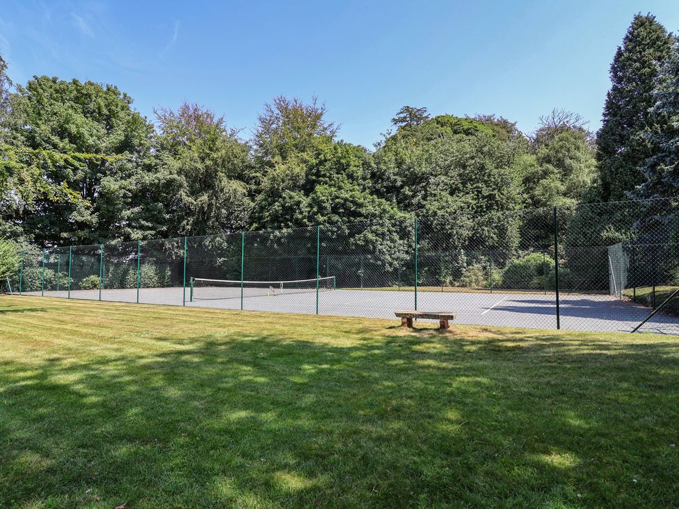 A tennis court with a fence and a bench at Parkfields House Tittensor near Barlaston