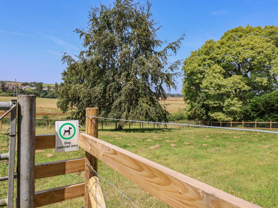 A dog exercise area with grassy field and trees at Parkfields House Tittensor near Barlaston