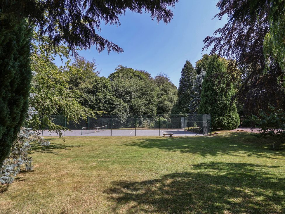 A garden with a tennis court surrounded by trees at Parkfields House Tittensor near Barlaston