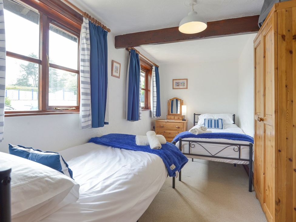 A bedroom with two beds and a wardrobe at Pillhead Cart Linhay in Bideford