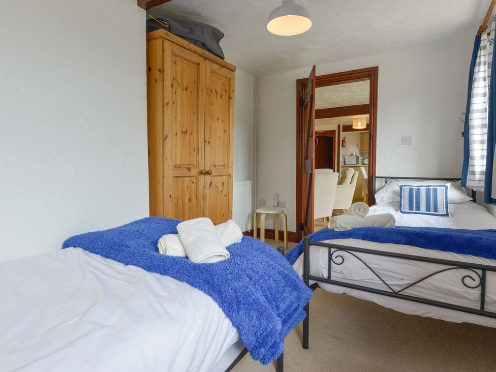 A bedroom with two beds and a wardrobe at Pillhead Cart Linhay in Bideford