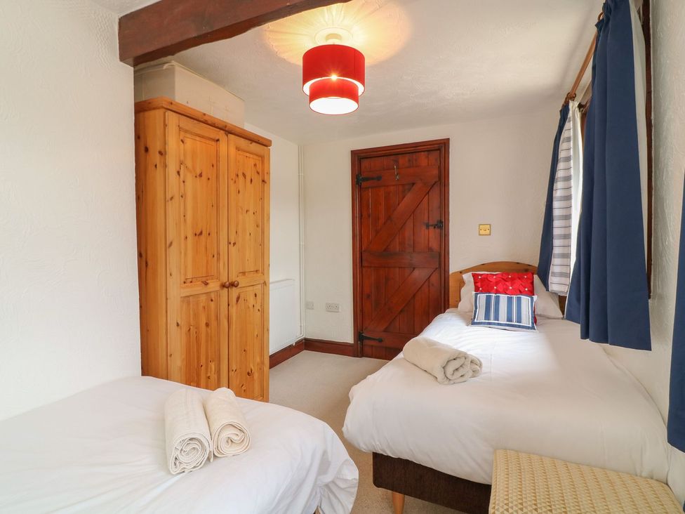 A bedroom with two beds and a wardrobe at Pillhead Cart Linhay in Bideford