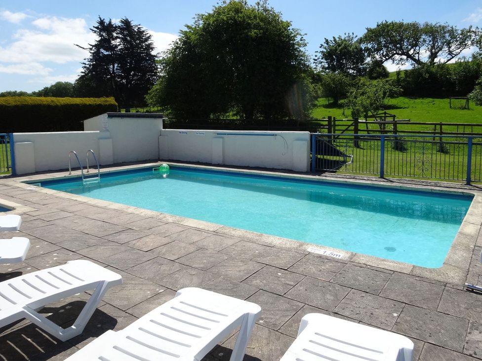 A swimming pool with loungers in an outdoor setting at Pillhead Cart Linhay in Bideford