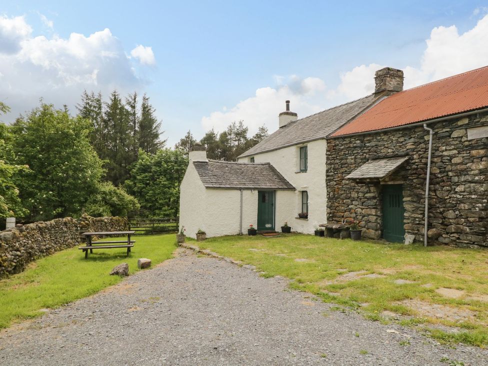 An outdoor view of a house with a bench and trees at Brigg House in Broughton-in-Furness