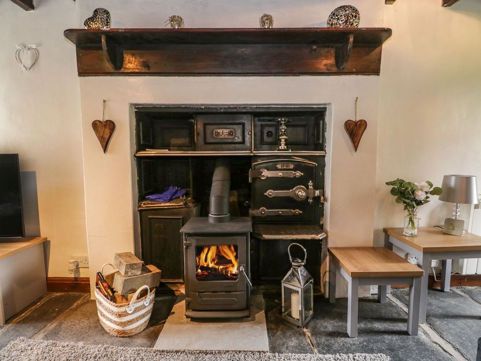 A living room with a wood stove and wooden shelves at Brigg House in Broughton-in-Furness
