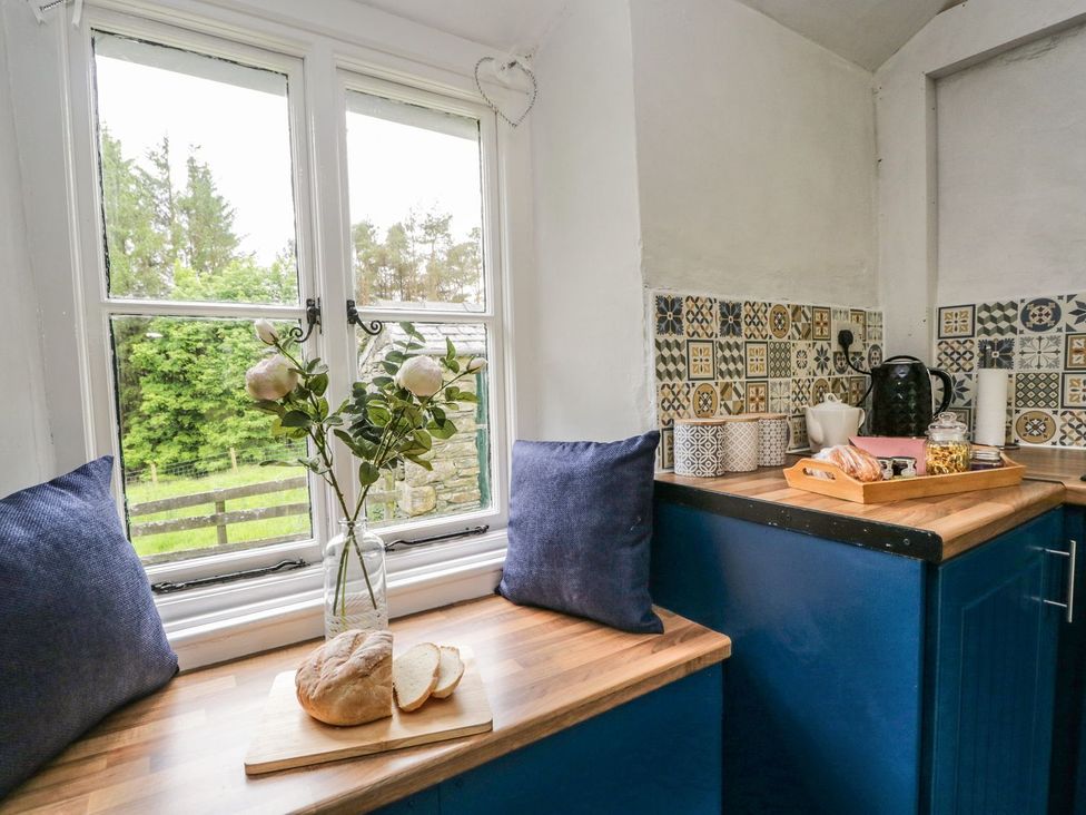 A kitchen with a window and flowers on a table at Brigg House in Broughton-in-Furness