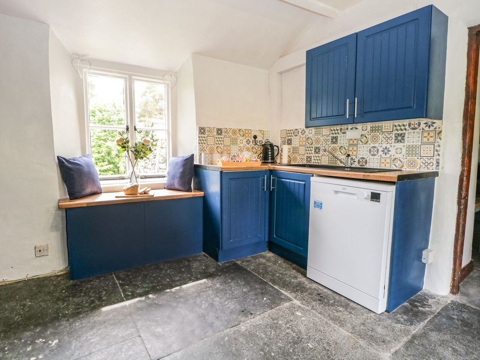 A kitchen with blue cabinets and a window seat at Brigg House in Broughton-in-Furness