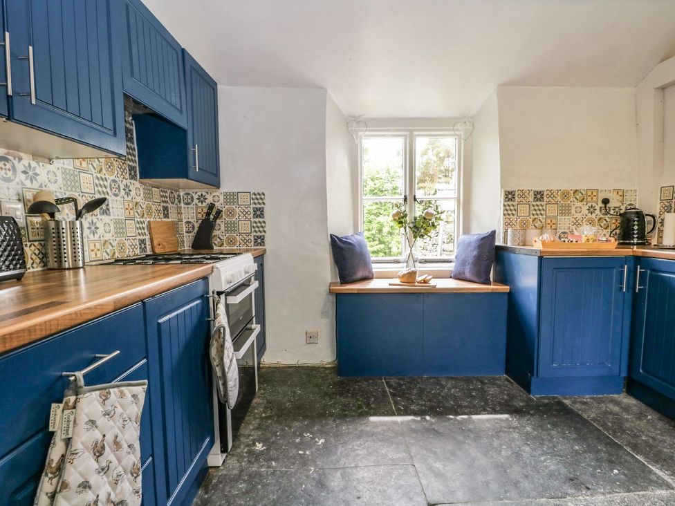 A kitchen with blue cabinets and a window seat at Brigg House in Broughton-in-Furness