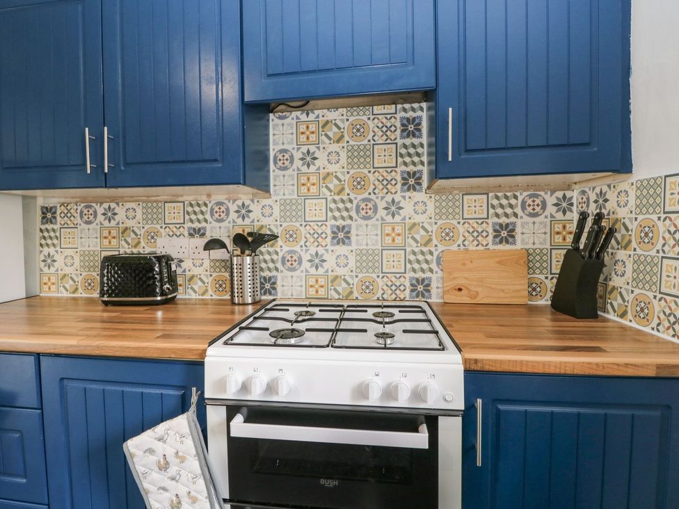 A kitchen with blue cabinets and a gas stove at Brigg House in Broughton-in-Furness