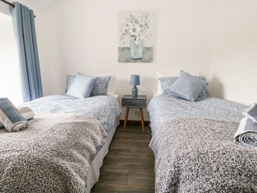 A bedroom with two beds and a nightstand at Brigg House in Broughton-in-Furness
