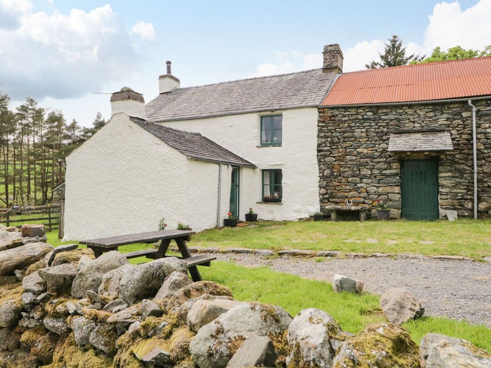 A cottage with a stone wall and a table at Brigg House in Broughton-in-Furness