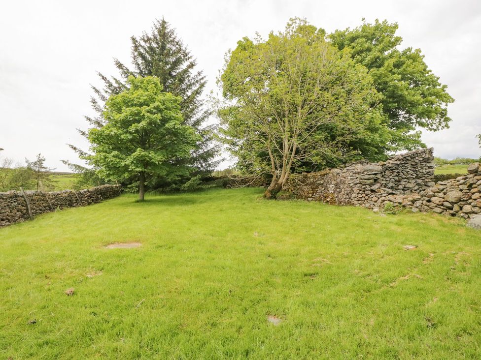 A garden with trees and stone walls at Brigg House in Broughton-in-Furness