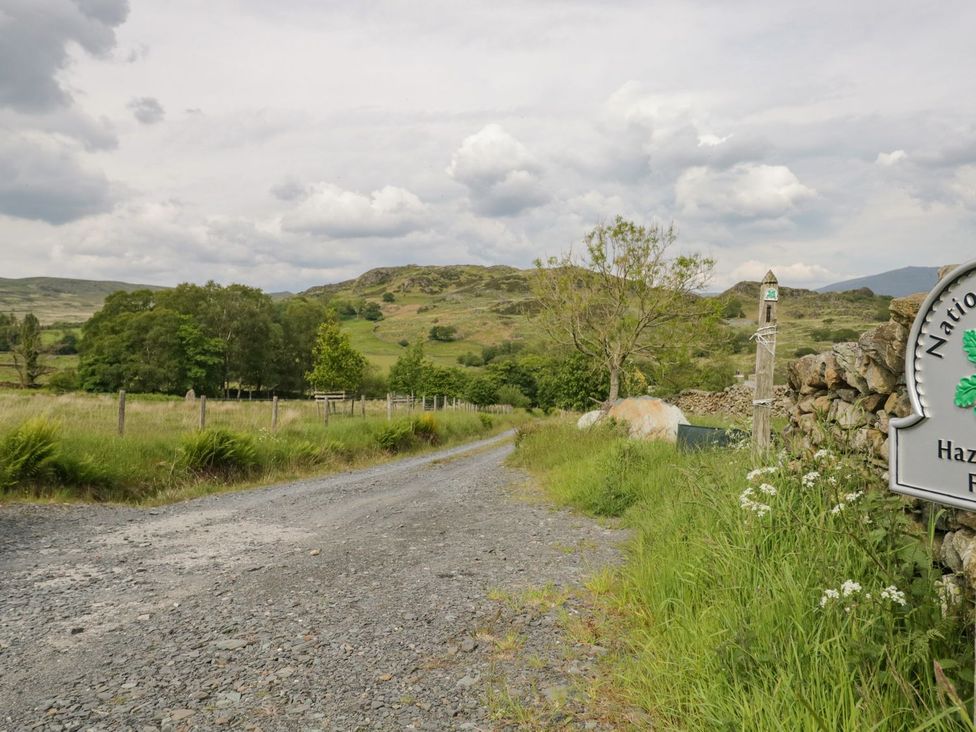 A gravel road with trees and a sign at Hazelslack in Broughton-in-Furness