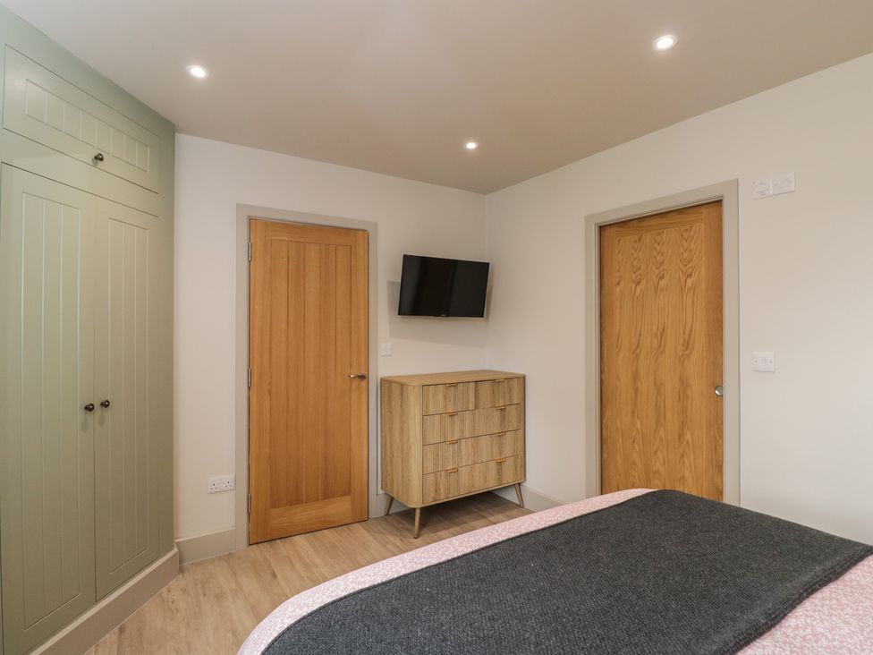 A bedroom featuring a bed, wardrobe, dresser, and television at Foxglove in Stratton Audley near Bicester