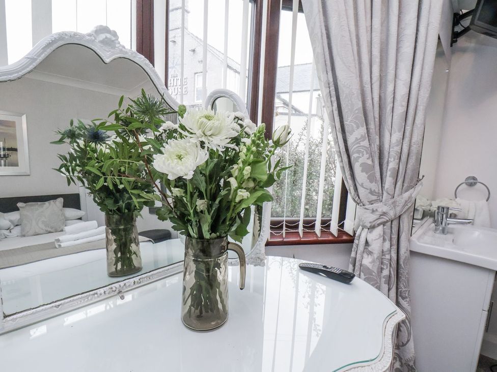 A bedroom with flowers in a vase on a table at Beachcrest in Whitby