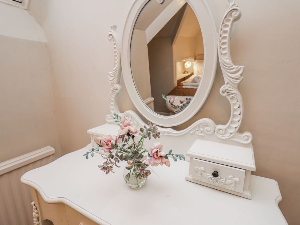 A dressing table with a mirror and a flower vase at Beachcrest in Whitby
