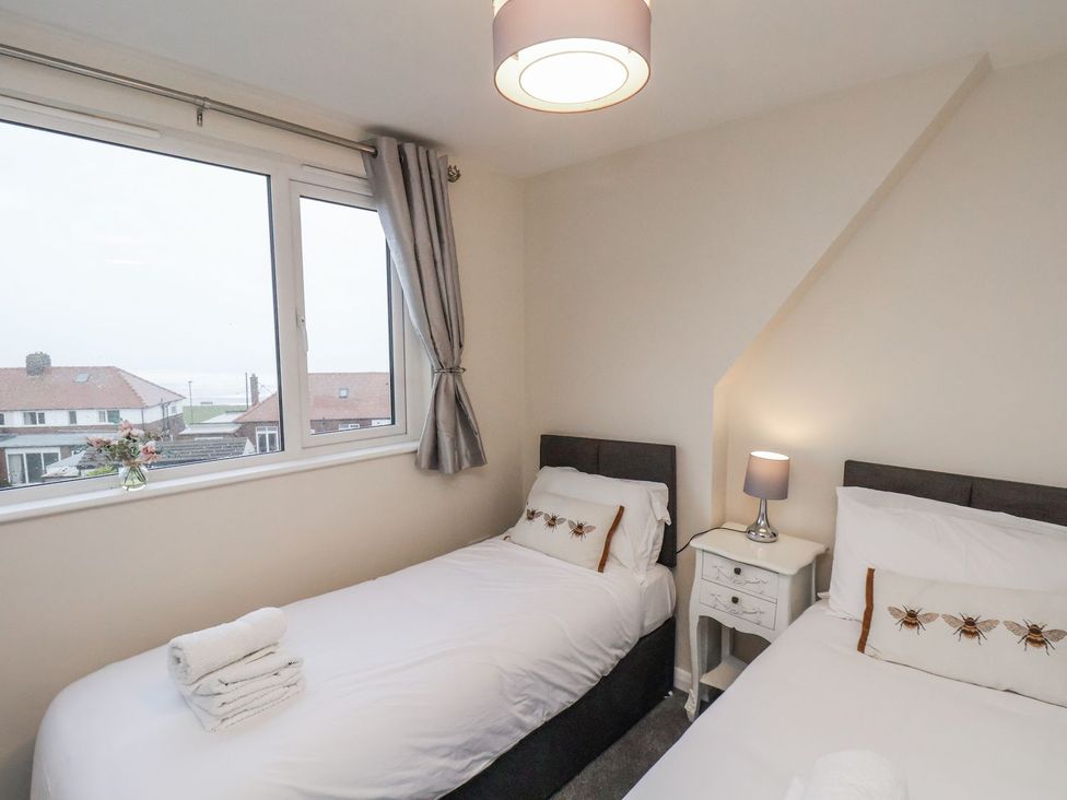 A bedroom with two beds and a bedside table at Beachcrest in Whitby