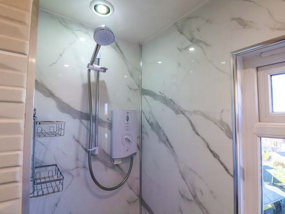A shower with marble walls and a window at Beachcrest in Whitby