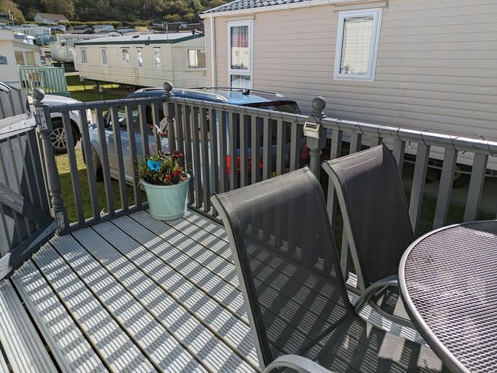 An outdoor deck with a table and chairs at Clarach Bay Holiday Village W18 Aberystwyth