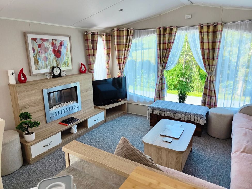 A living room with a fireplace and television at Clarach Bay Holiday Village W18 Aberystwyth