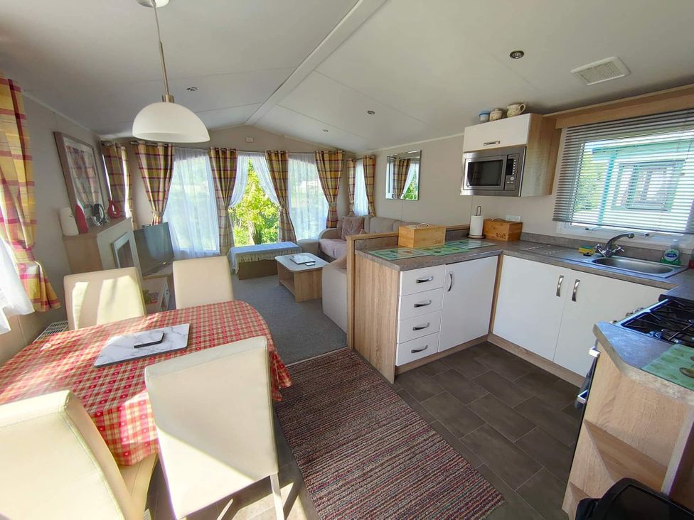A kitchen with dining table and sofa at Clarach Bay Holiday Village W18 Aberystwyth