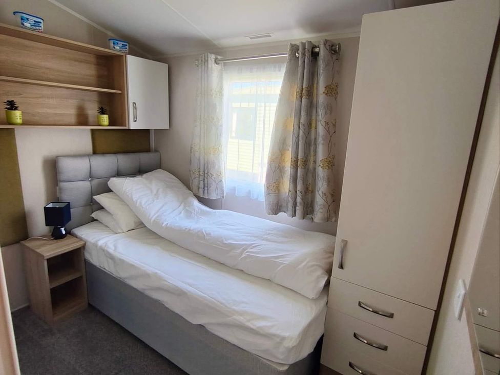 A bedroom with a single bed and a shelf at Clarach Bay Holiday Village W18 Aberystwyth