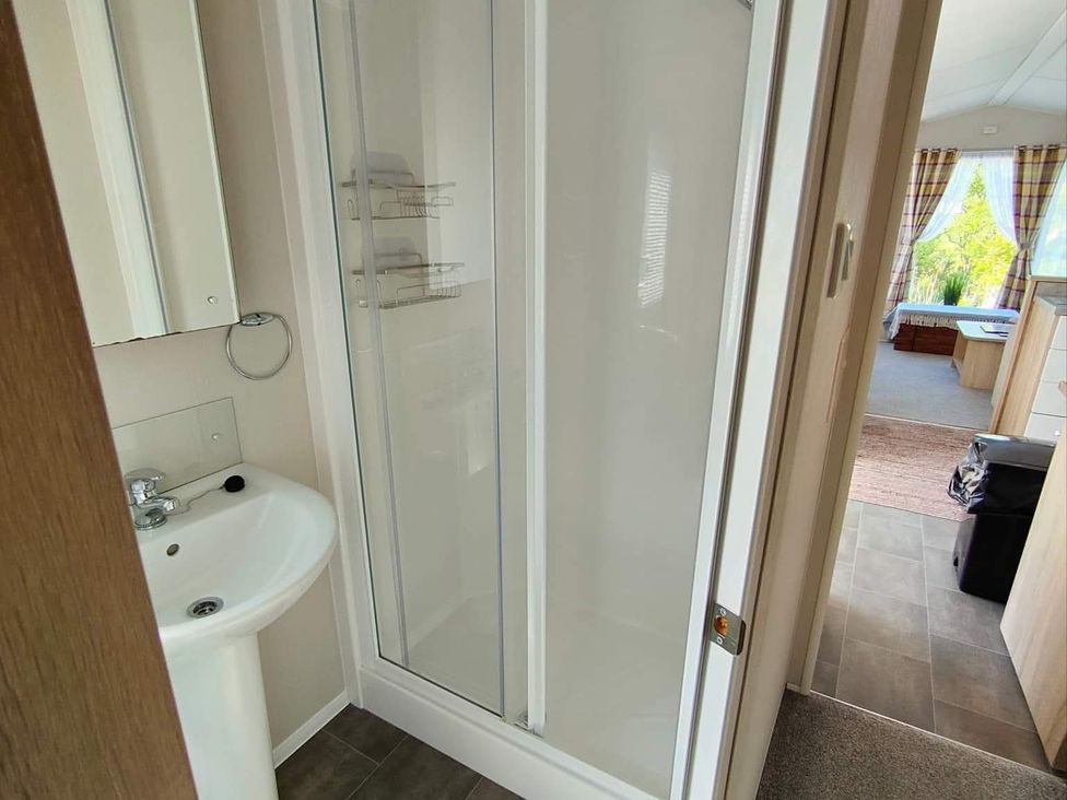 A bathroom with a shower and sink at Clarach Bay Holiday Village W18 Aberystwyth