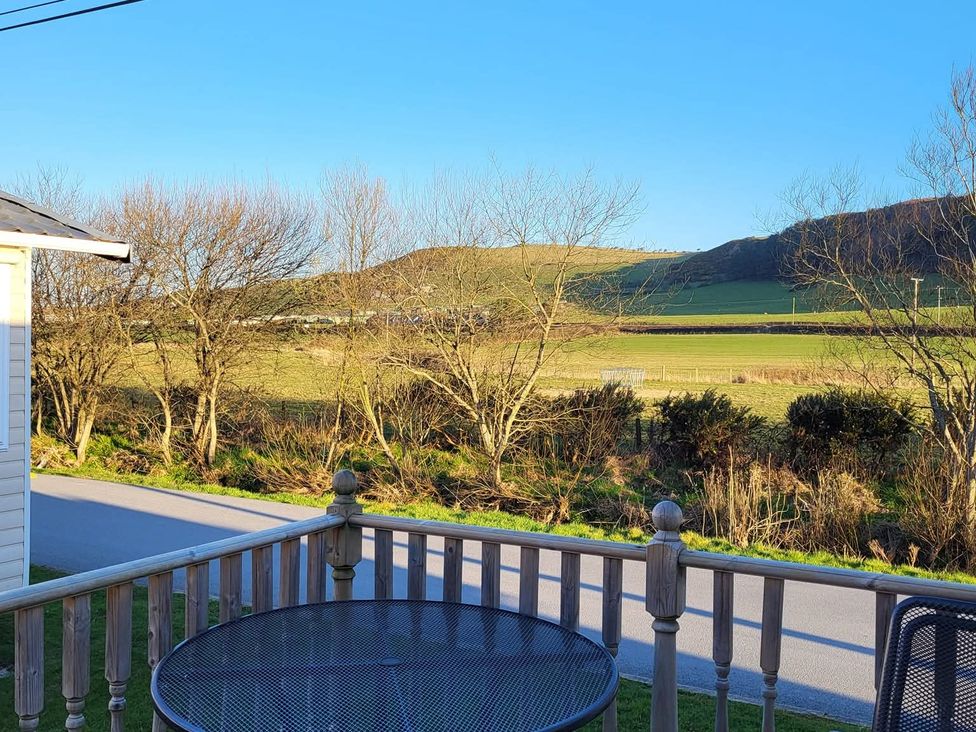 A view from a deck with a table and chairs overlooking a field at Clarach Bay Holiday Village W18 Aberystwyth