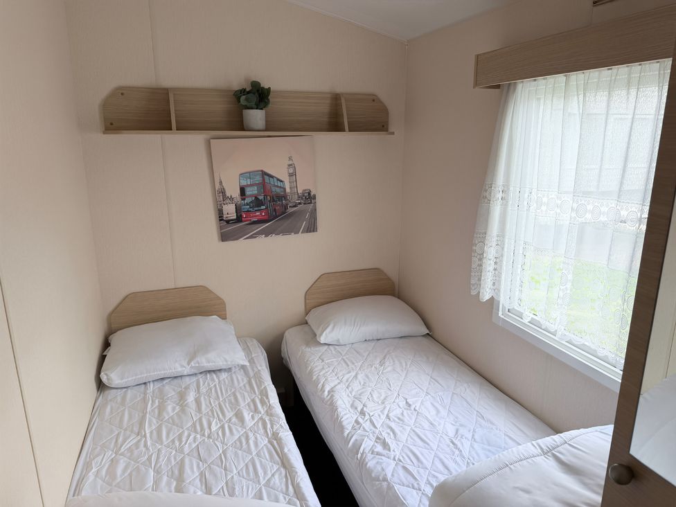 A bedroom with two beds and a picture on the wall at Holiday Park Seawick Clacton-on-Sea