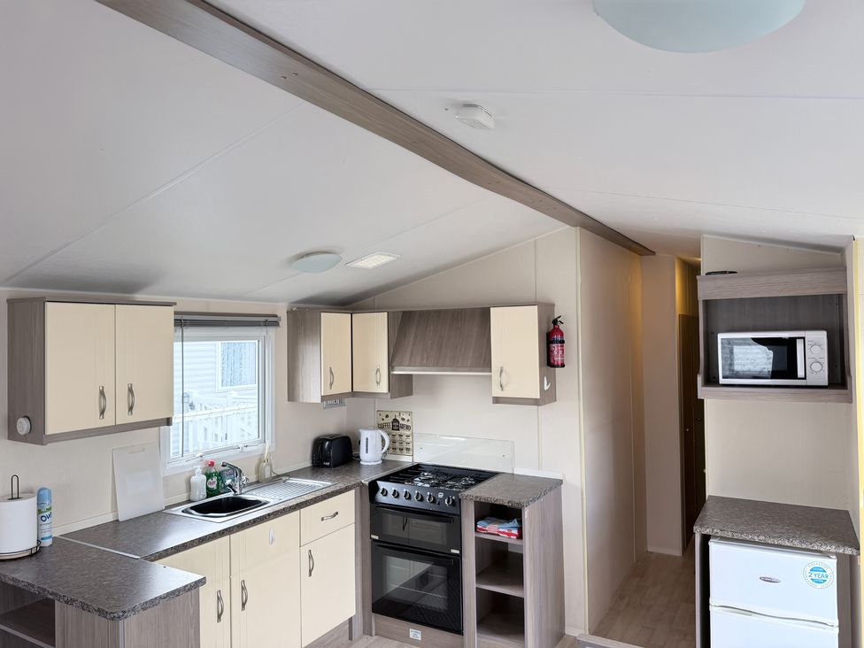 A kitchen with cabinets, stove and sink at Holiday Park Seawick in Clacton-on-Sea