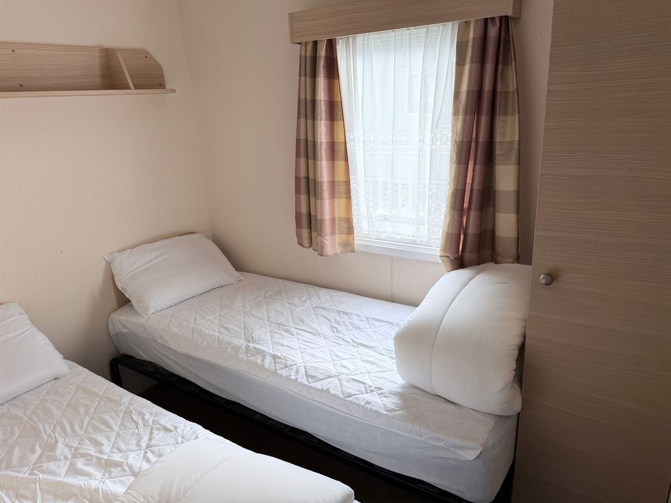 A bedroom with two beds and a window at Holiday Park Seawick Clacton-on-Sea