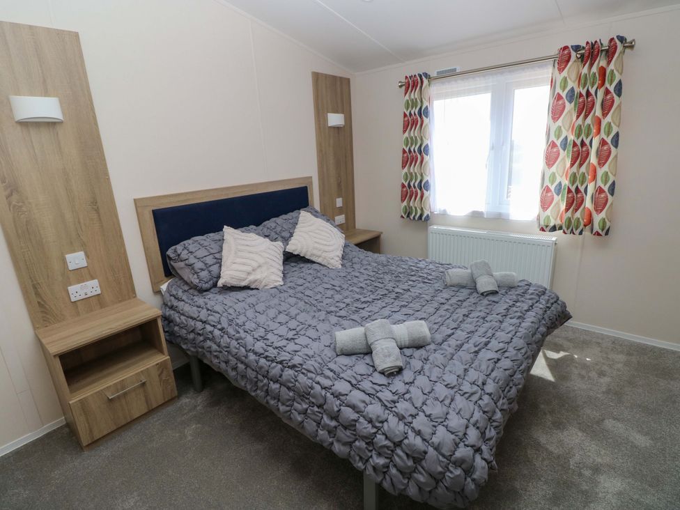 A bedroom with a double bed and nightstand at Sandpiper in Narberth