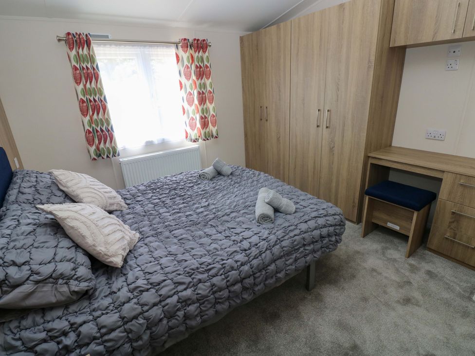 A bedroom with a bed and wardrobe at Sandpiper in Narberth