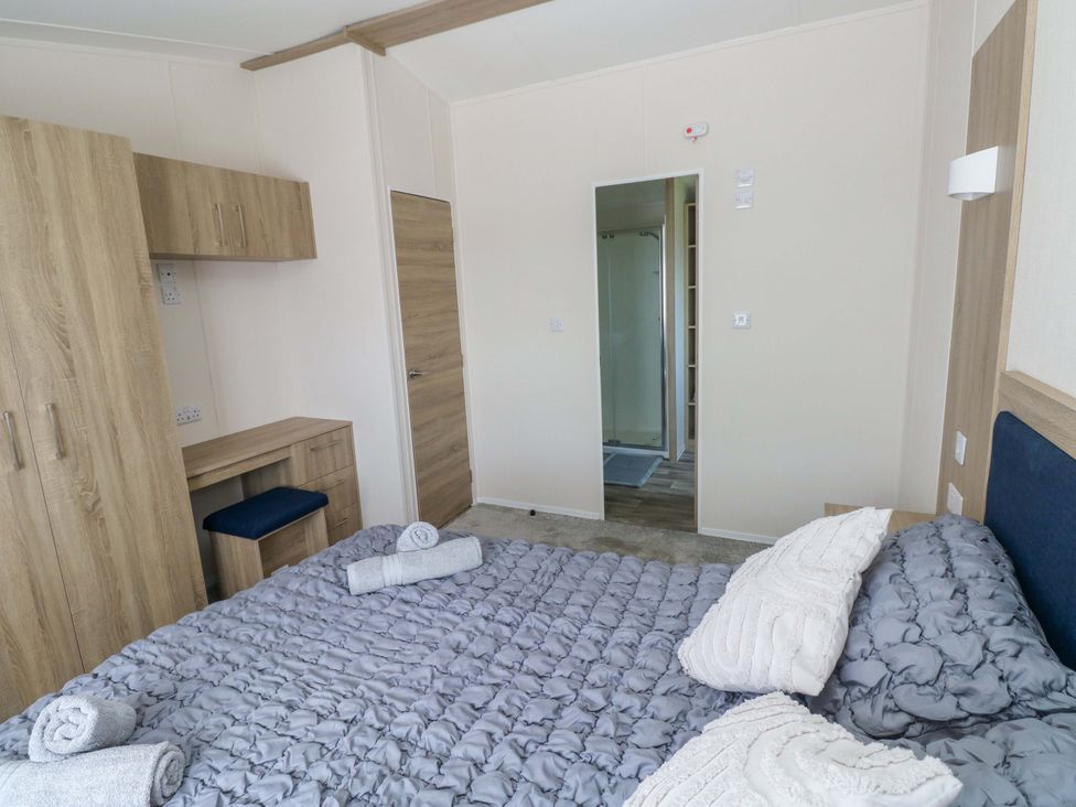 A bedroom with a bed and wardrobe at Sandpiper in Narberth