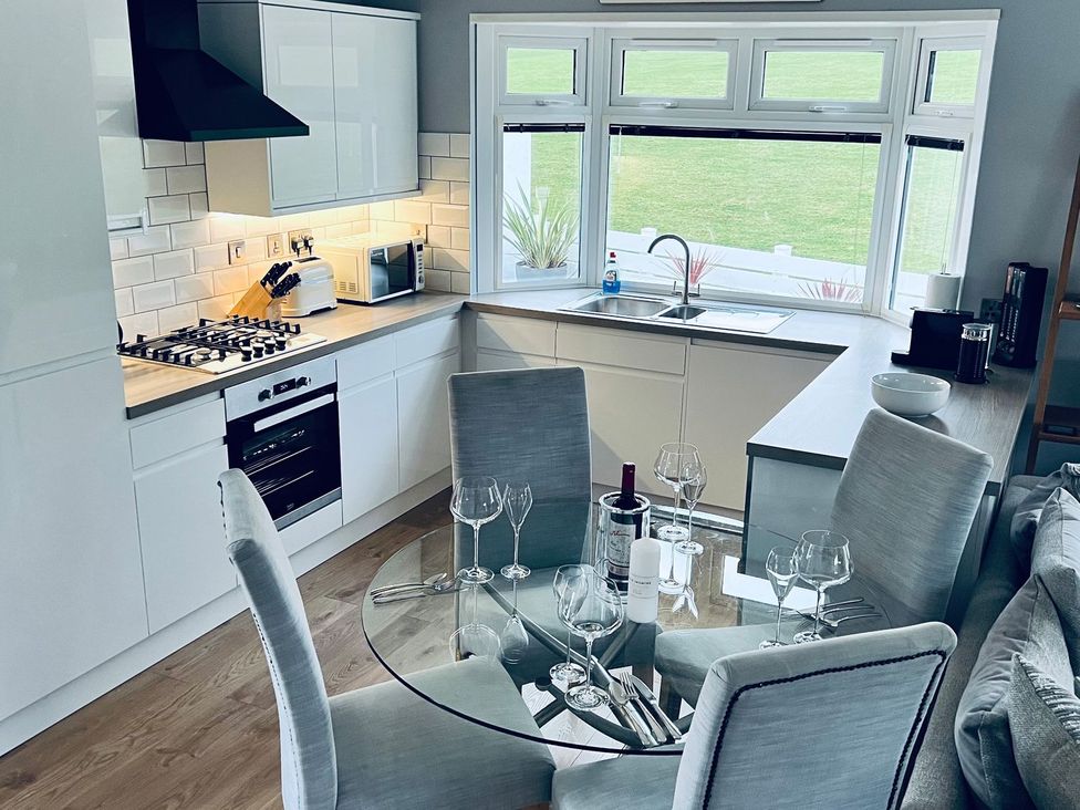 A kitchen with a round dining table and chairs at O7 in Abersoch