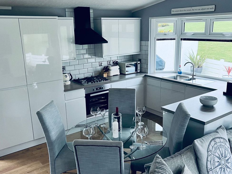 A kitchen with a dining table and glassware at O7 in Abersoch