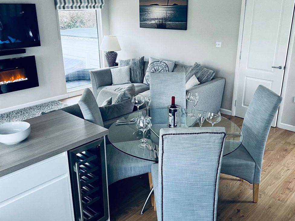 A dining room with a glass table and wine bottles at O7 Abersoch