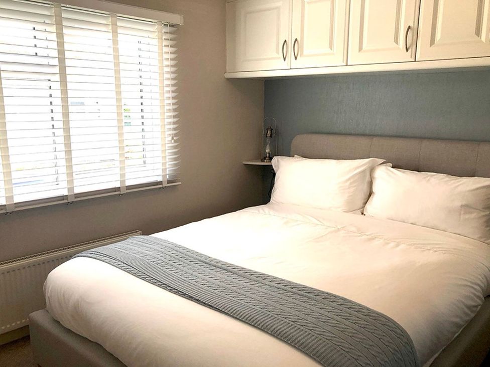 A bedroom with a bed and shelves at O7 in Abersoch