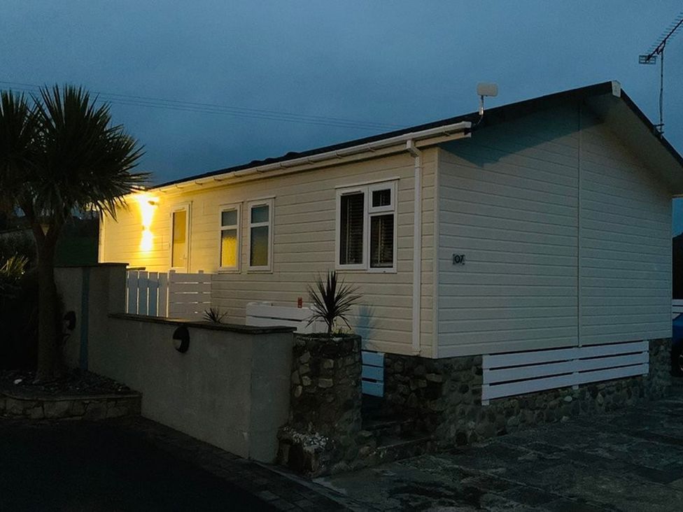 A house with a stone wall and palm tree at O7 in Abersoch