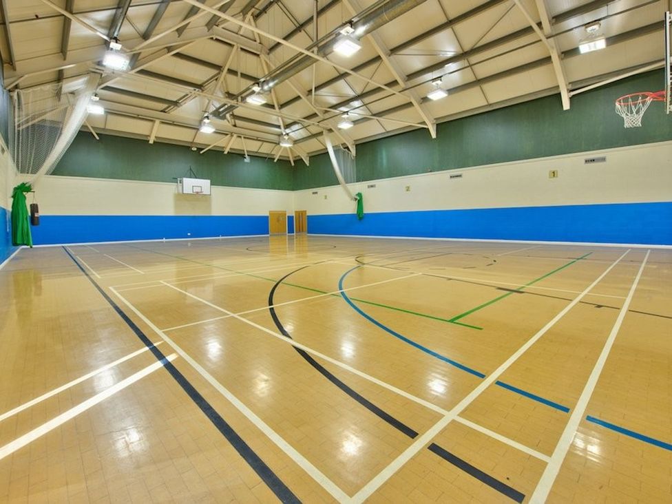 A sports hall with court lines and a basketball hoop at O7 in Abersoch