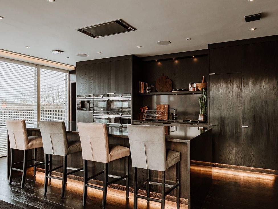 A kitchen with bar stools and dark cabinets at The Penthouse in Shrewsbury