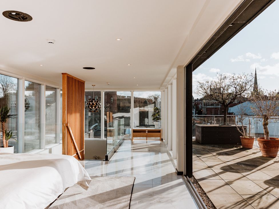 A bedroom with a bed and windows at The Penthouse in Shrewsbury